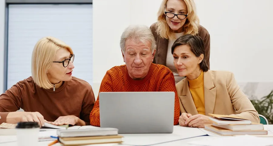 Diverses persones adultes consulten juntes un ordinador portàtil